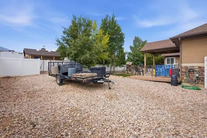 Gravel yard area featuring a vinyl fence and a covered wood deck