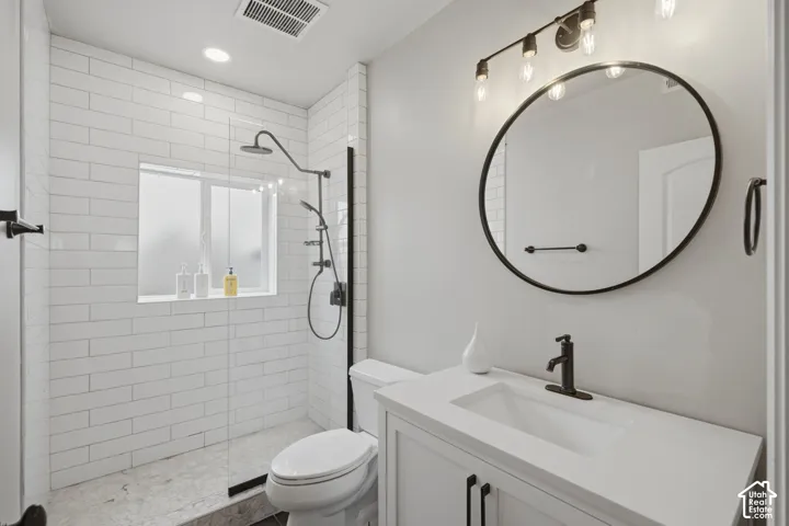 Modern bathroom featuring a walk-in shower with white subway tile, a dark-framed glass enclosure, and a built-in window