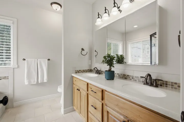 Double vanity featuring light wood cabinetry, white countertops, and dual undermount sinks
