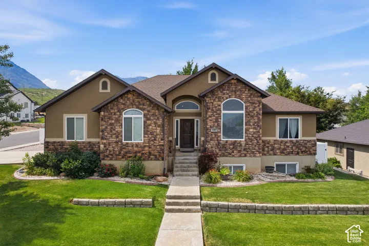 Symmetrical facade featuring stone veneer accents, arched entry window, and an arched door with sidelights