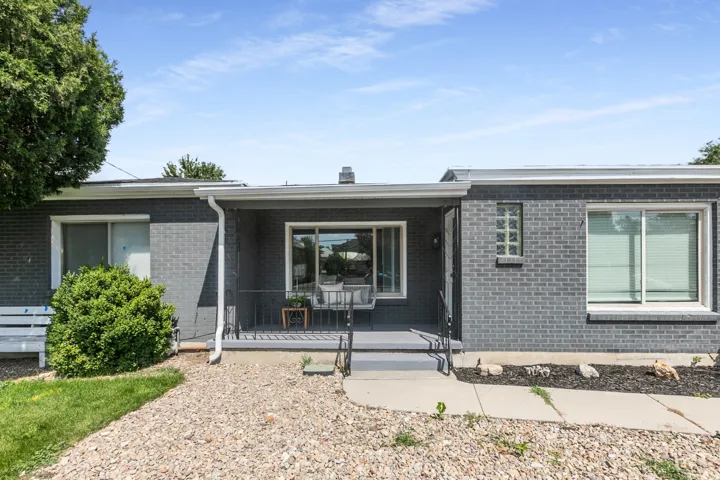 Gray brick exterior featuring a covered front porch, white window trim, and a glass block window accent