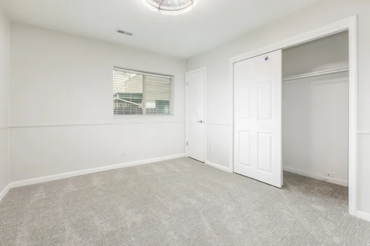 Neutral-toned room featuring light gray carpeting and white walls with wainscoting