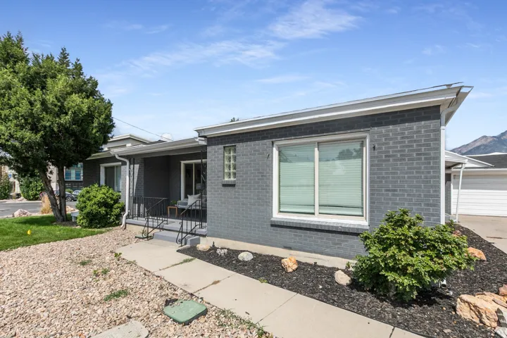 Dark gray brick exterior with white trim and a covered front porch featuring black railings