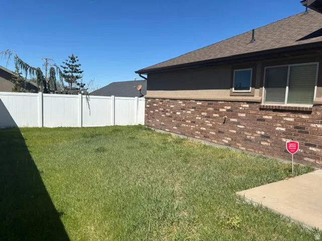 Expansive green lawn area featuring a white privacy fence
