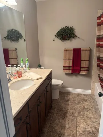 Bathroom featuring a dark wood-finish vanity with a single basin sink and light-colored countertop