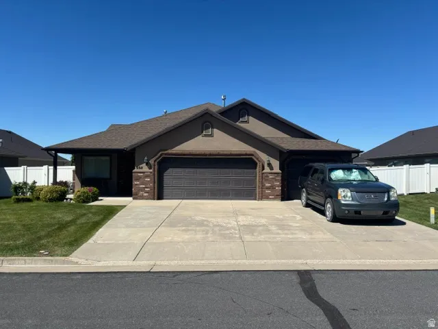 Ranch-style residence featuring a stucco exterior with brick accents, a two-car garage, and a covered entry