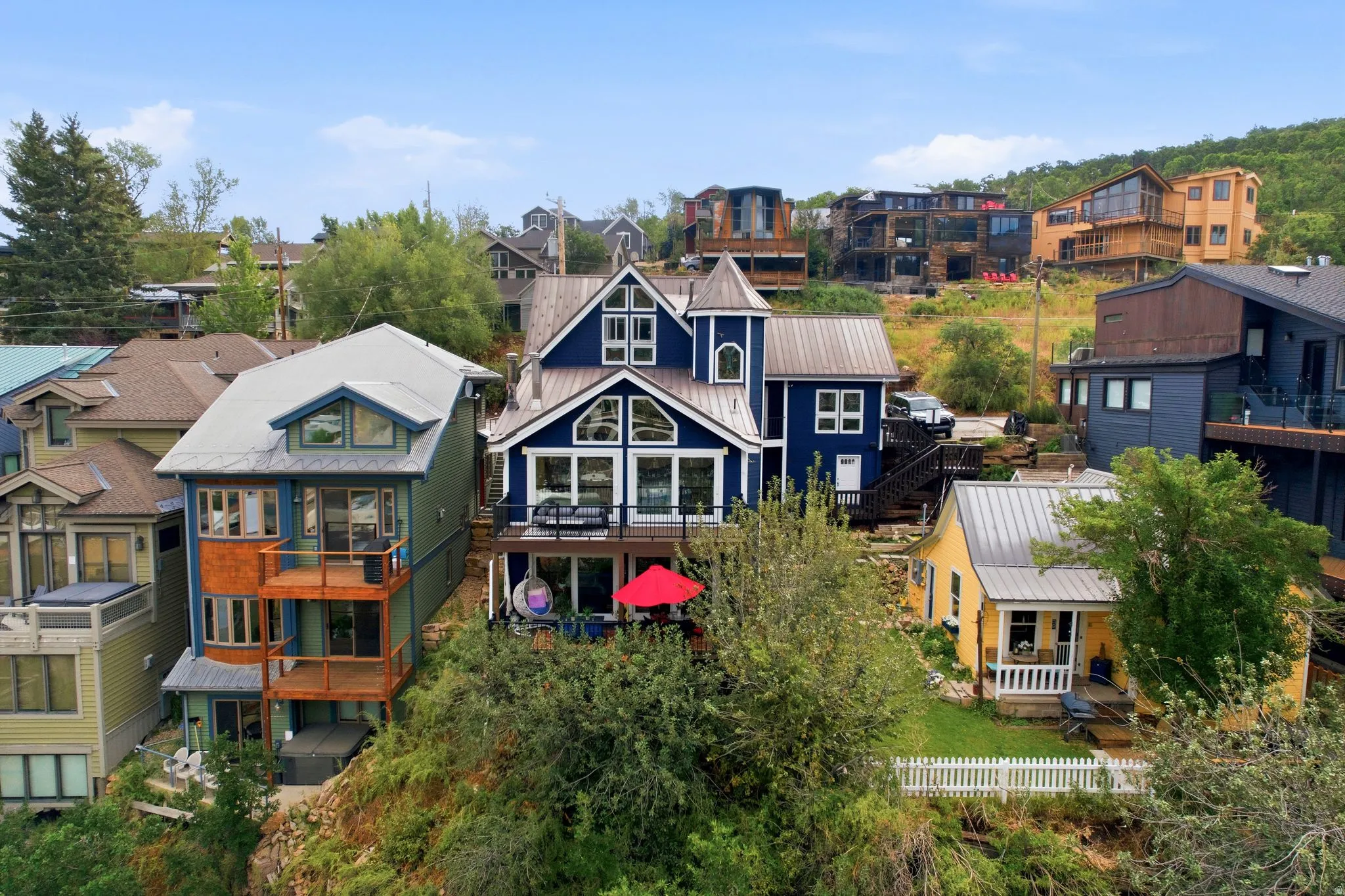 Multi-level blue residence featuring a turret accent, multiple gabled windows, and a lower-level deck