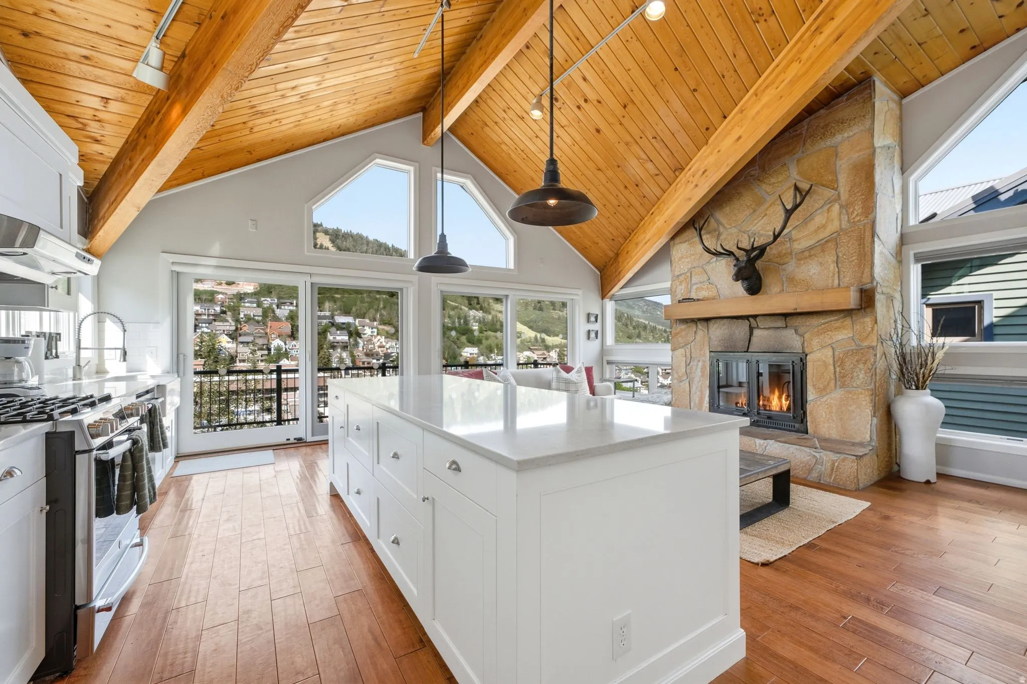 Open-concept kitchen featuring a large central island with a solid surface countertop, stainless steel range with overhead ventilation, and wood-finish flooring