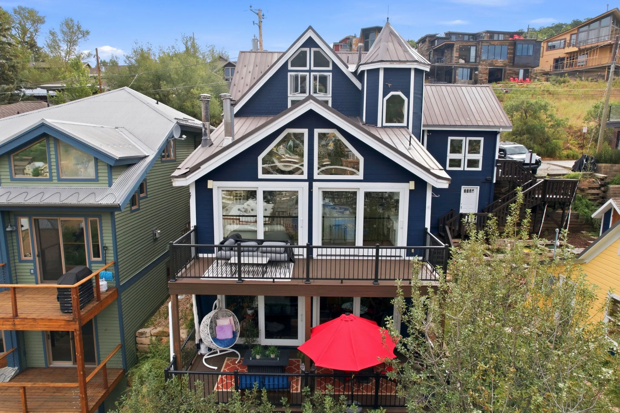 Navy blue exterior featuring a turret, multiple balconies, a metal roof, and abundant window placements