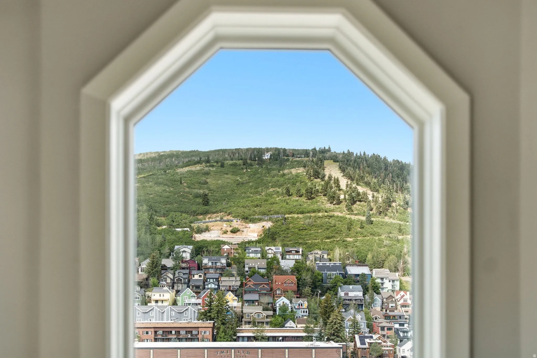 Octagonal window framing a mountain and residential area