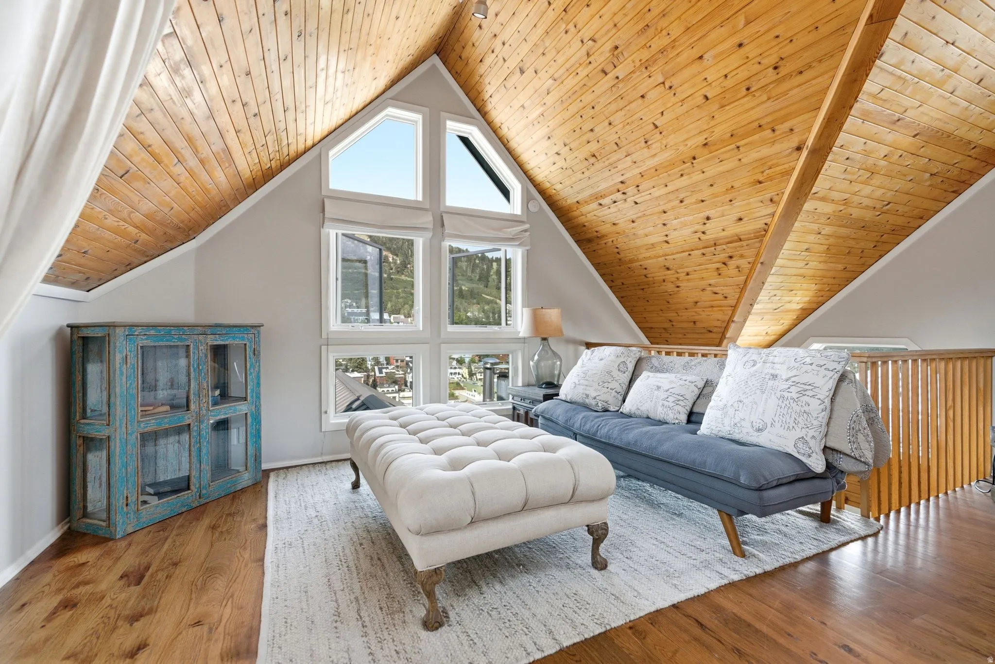 Vaulted wood-paneled ceilings with exposed beams, wood-finish flooring, and expansive window walls offering mountain scenery