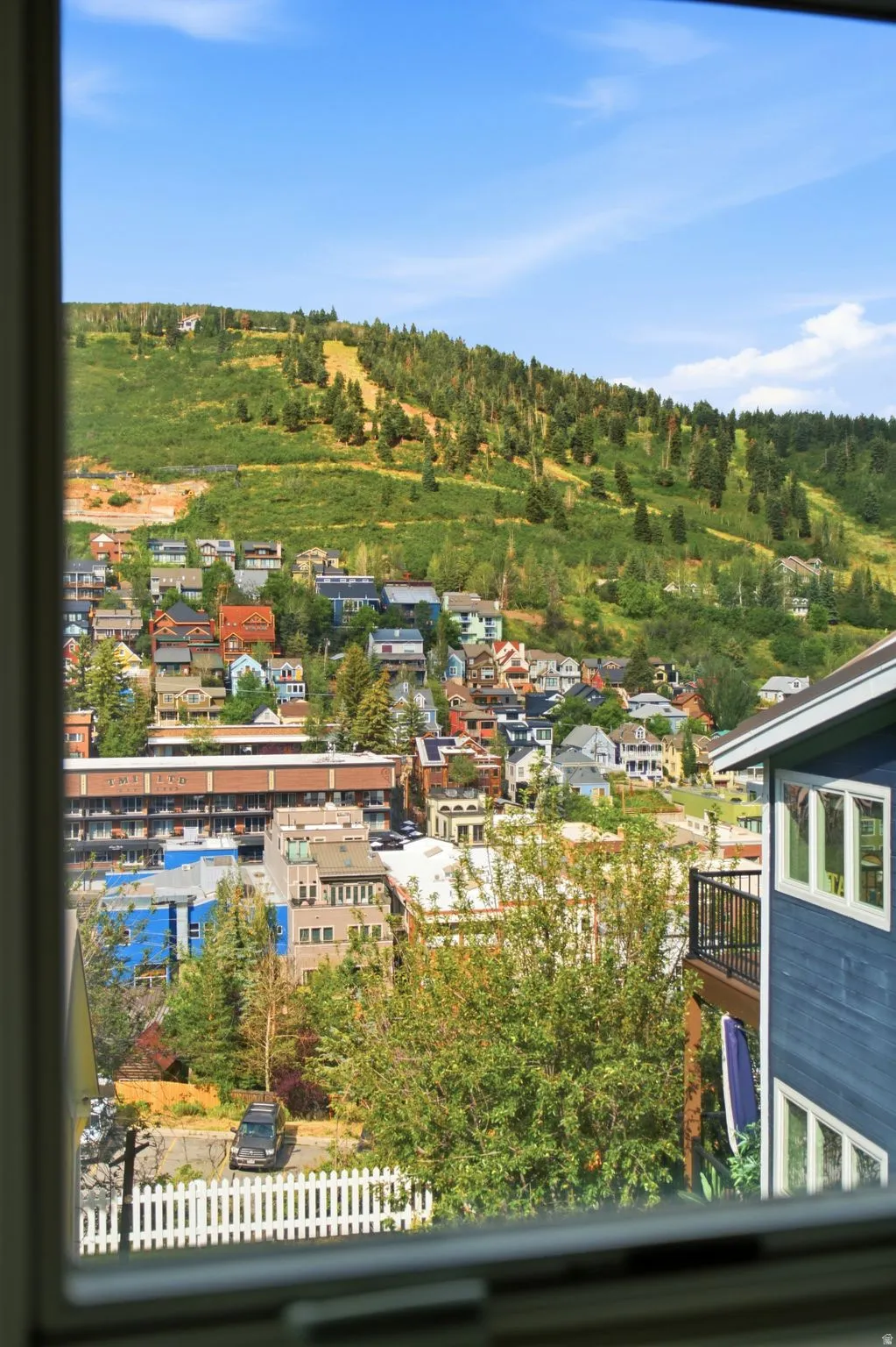 Expansive hillside scenery featuring a vibrant townscape, lush green trees, and mountain terrain