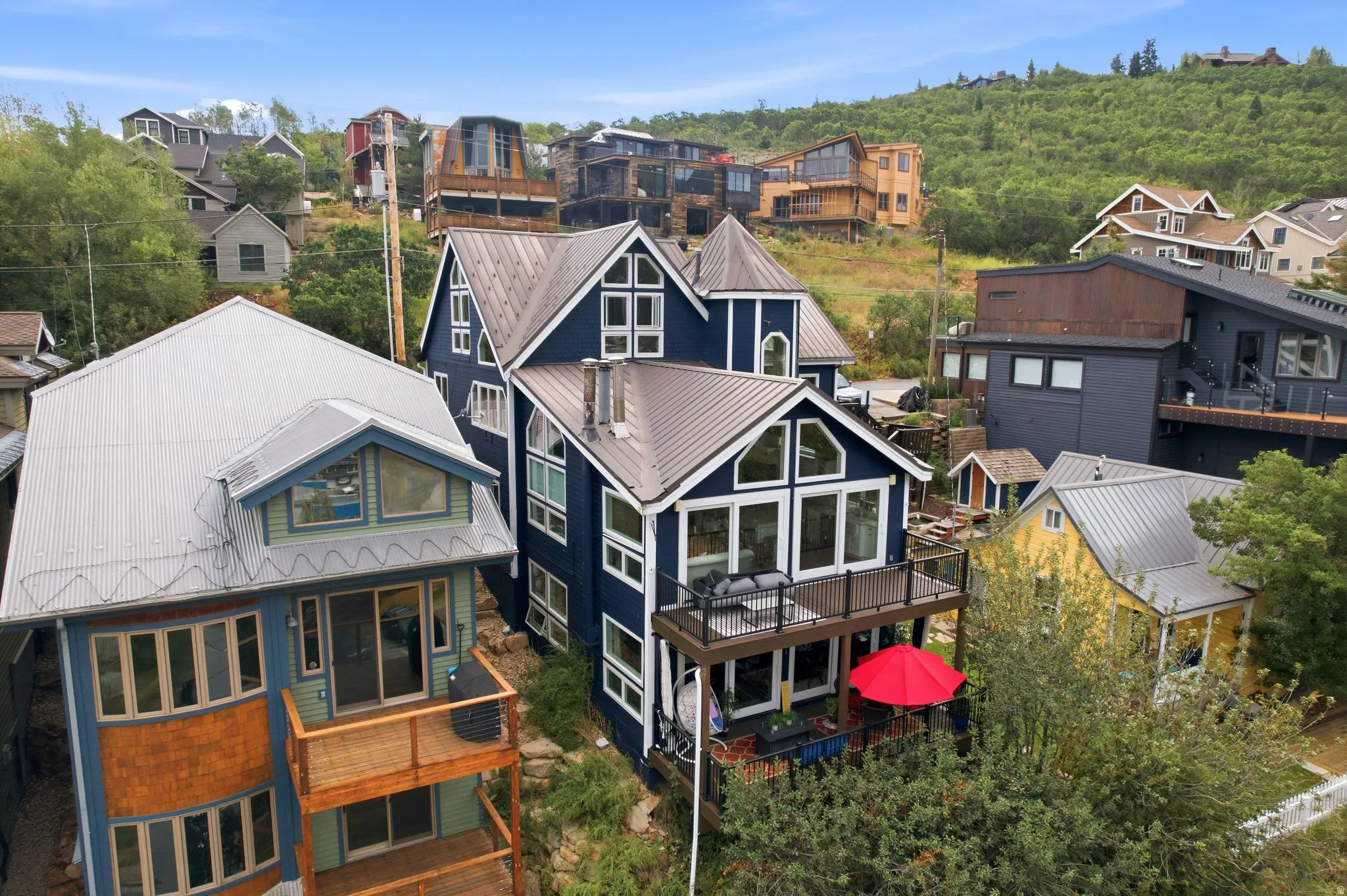 Contemporary blue multi-level residence with extensive white trim, featuring multiple gabled roofs with metal roofing