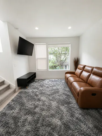 Living area featuring recessed lighting, dual windows with roller shades, and a wall-mounted display