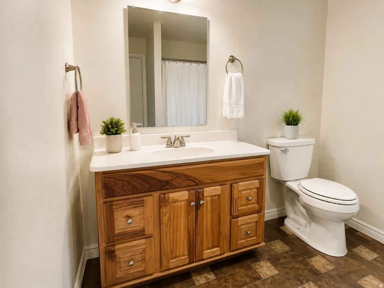 Bathroom featuring a wood-finish vanity with a white countertop and integrated sink, a commode, and a shower with a white curtain