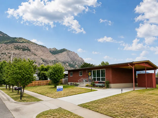 Single-story brick residence featuring a carport, front yard, and concrete driveway
