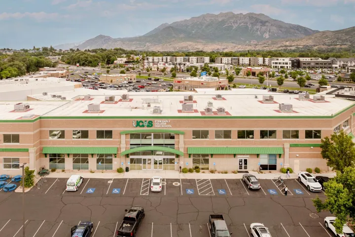 Multi-story commercial building featuring a light tan facade with green accents and multiple windows