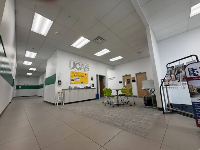 Open interior space featuring a drop ceiling with recessed lighting, tile flooring, and a carpeted section