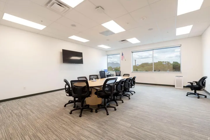 Spacious interior featuring a large conference table, textured carpet flooring, and expansive windows