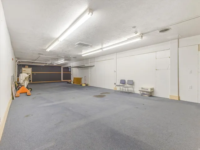 Spacious interior featuring commercial-grade carpet flooring and a suspended acoustic ceiling with fluorescent lighting