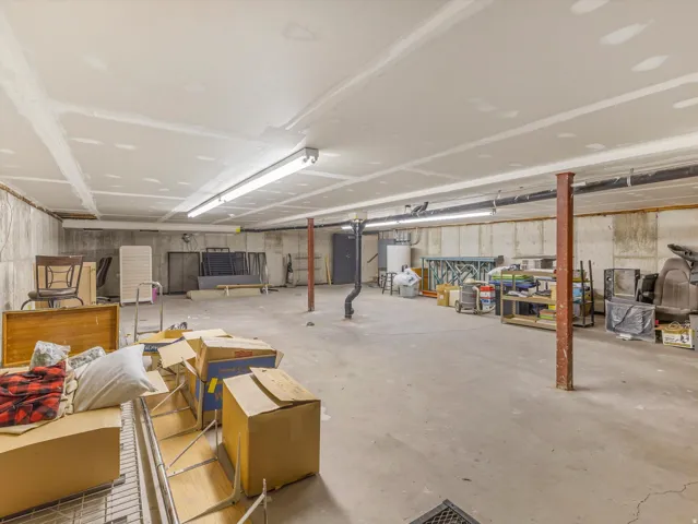 Expansive unfinished basement featuring concrete flooring, concrete walls, and overhead fluorescent lighting