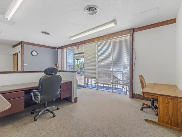 Open-concept office space featuring carpet flooring and wood-beam accents