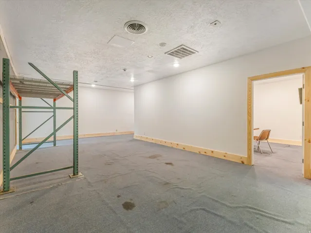 Spacious interior with neutral white walls, recessed lighting, baseboard trim, and a carpeted floor