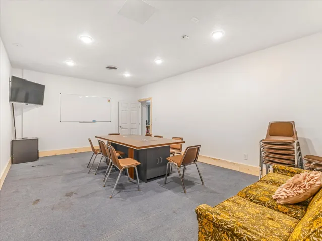 Versatile interior space featuring recessed lighting, a mounted wall screen, and a whiteboard