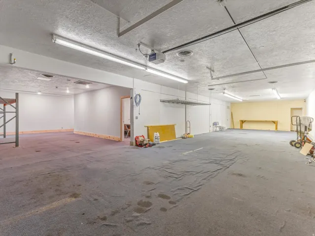 Expansive open-plan commercial space featuring textured ceilings and fluorescent lighting
