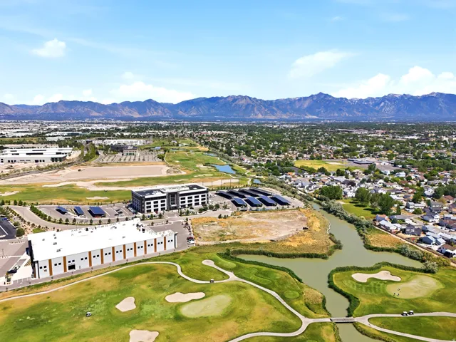 Expansive aerial perspective showcasing a golf course with water features and sand traps, surrounded by residential areas and commercial buildings