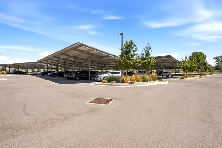 Expansive covered parking structure featuring multiple bays, integrated lighting fixtures, and surrounding landscaping