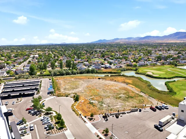 Expansive land parcel featuring open terrain, bordered by a golf course, bodies of water, and residential areas