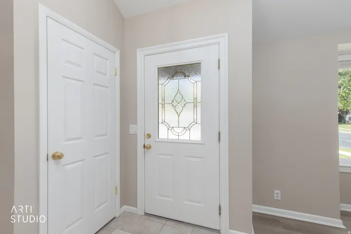 Entryway featuring a decorative glass panel door, neutral wall paint, and a tiled floor