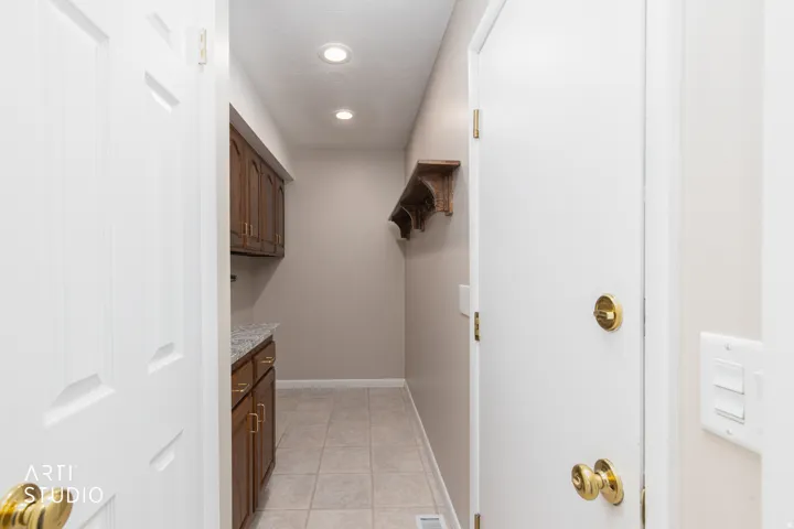 Utility area featuring wood cabinetry with brass hardware, speckled countertop, and recessed lighting