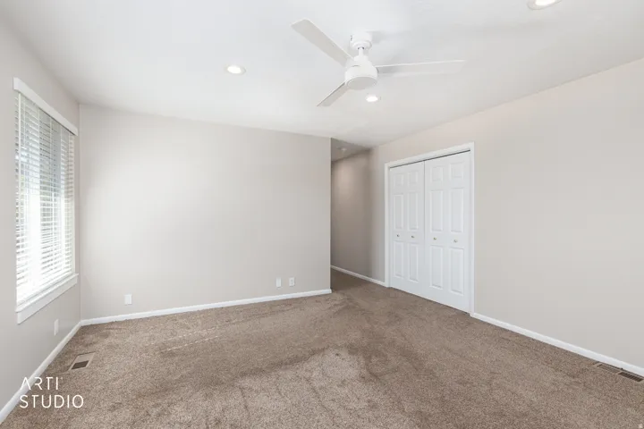 Carpeted room featuring a ceiling fan, recessed lighting, double bi-fold closet doors, and a window with horizontal blinds