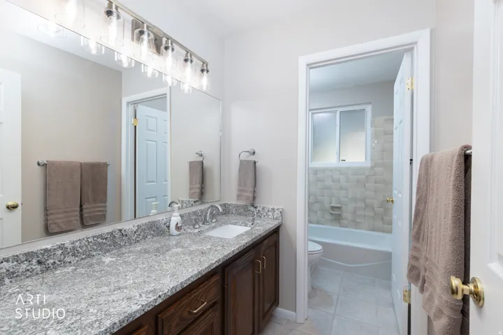 Bathroom vanity featuring a speckled countertop, a rectangular undermount sink, and a brushed nickel faucet