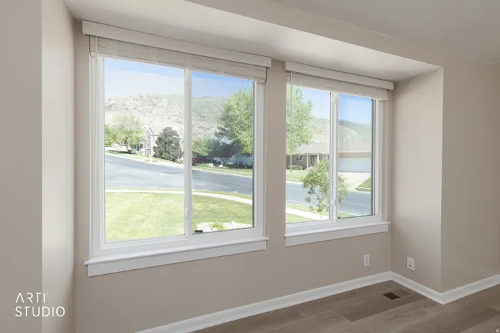Bright interiors featuring two large windows, wood-finish flooring, white baseboards, and neutral wall paint
