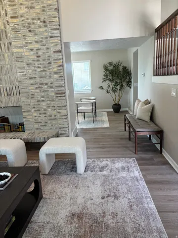 Open-concept interior featuring wood-finish flooring, a contemporary brick fireplace, and a light-filled dining area