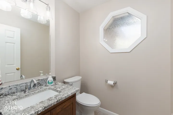 Powder room featuring a white paneled door, vanity with a speckled countertop, undermount sink, and chrome faucet