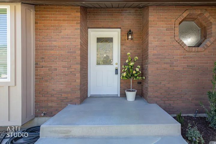 Brick exterior entrance featuring a white door with decorative glass