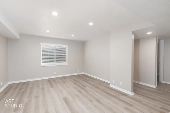 Spacious room featuring wood-finish flooring, recessed lighting, a window with blinds, and neutral wall tones