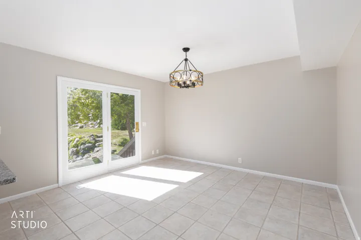 Spacious room featuring neutral-toned walls, tile flooring, and a contemporary chandelier
