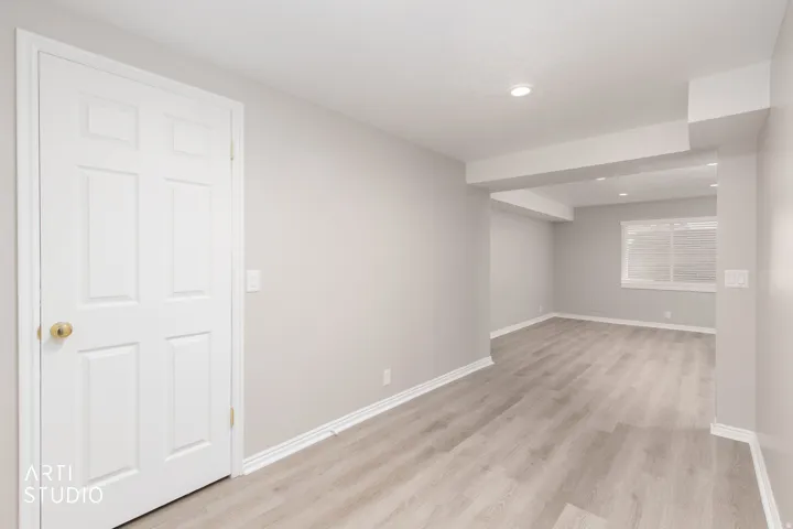 Spacious room featuring wood-finish flooring, recessed lighting, a window with horizontal blinds, and a white paneled door