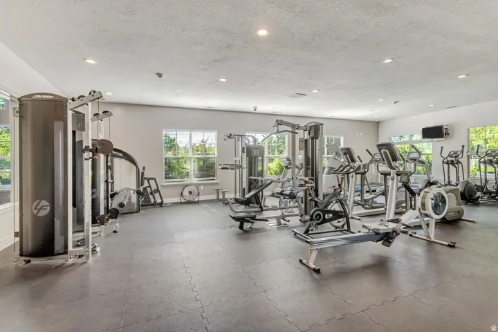 Clubhouse has a spacious fitness area featuring a variety of exercise equipment, recessed lighting, multiple windows, and durable interlocking floor mats