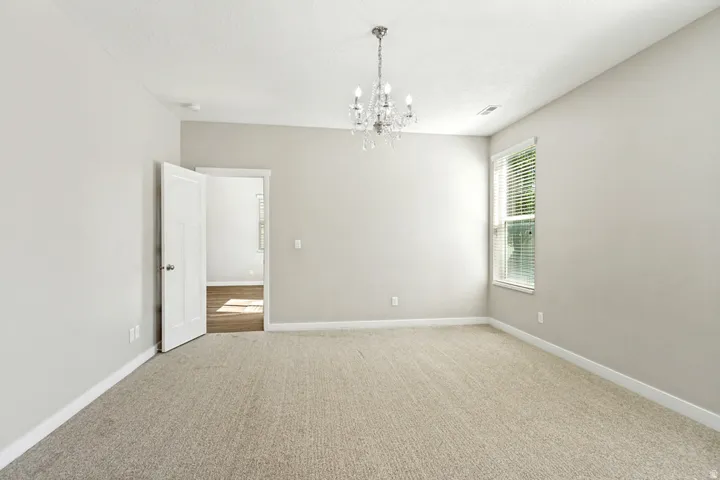Primary bedroom is spacious room featuring neutral carpeting and light-toned walls