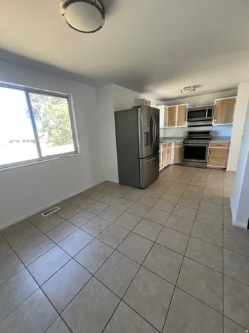 Kitchen featuring stainless steel appliances, wood-finish cabinetry, light-toned countertops, and tile flooring