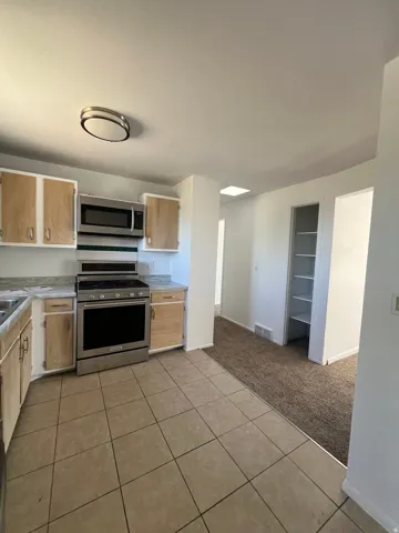 Kitchen featuring a tile floor, stainless steel range, and stainless steel microwave