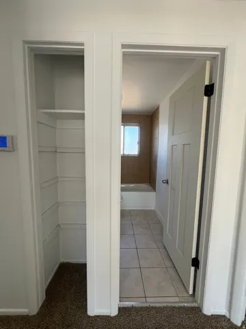 Built-in closet shelving, interior panel door, and tile flooring