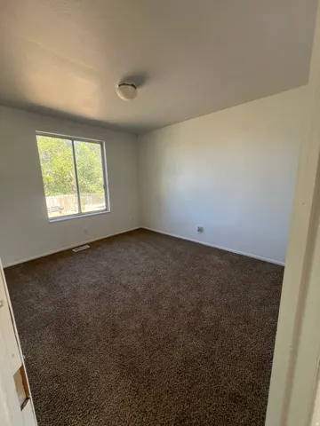 Broadloom carpet flooring in a neutral tone and a single window