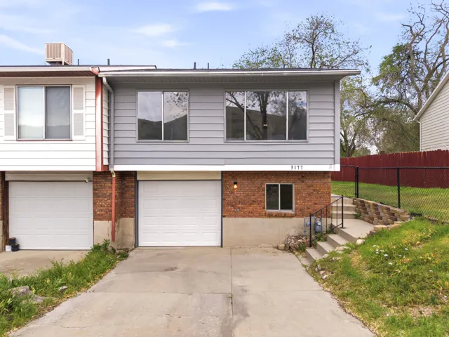 Contemporary duplex exterior with grey horizontal siding and a brick foundation
